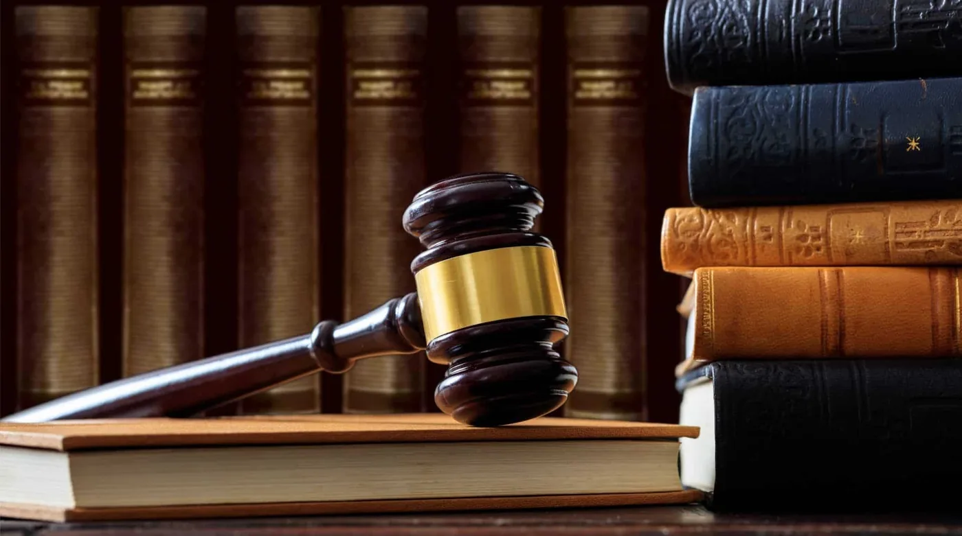 Judge's gavel resting on a law book beside a stack of legal volumes